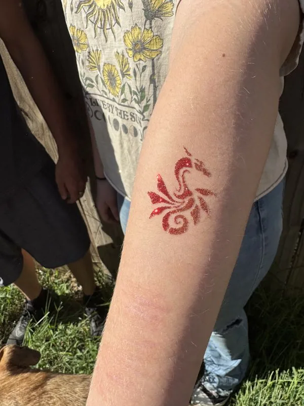 Red dragon glitter tattoo applied at a Texas party